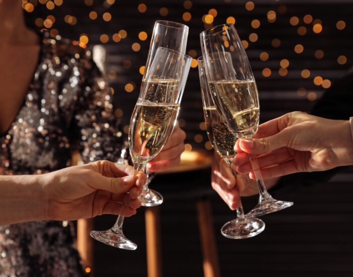 People clinking glasses of champagne indoors, closeup